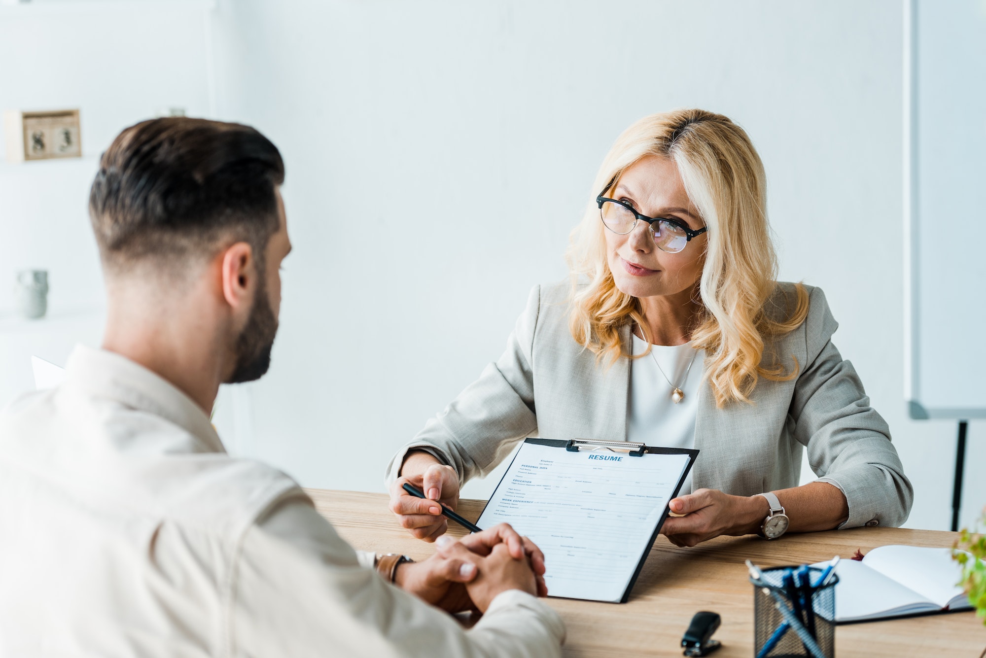 selective-focus-of-recruiter-in-glasses-holding-pen-near-clipboard-and-looking-at-bearded-man.jpg